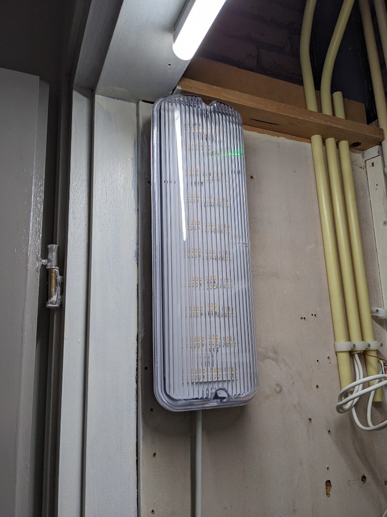 Foto van noodverlichting tegen een houten schot gemonteerd.